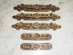 four antique brass drawer pulls on a marble surface