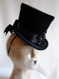 The Tease is a fabulous dark fashion lady's top hat,luxuriously elegant and feminine all the way! It is covered with rich black velvet and trimmed with black ribbon around the crown that ends in a beautiful double black bow at the back. The focal point is a majestic hand-beaded black crystal element at the side front that sparkles as you move around. Measurements : height 6.5 inches( 16 cm ) front to back 9 inches ( 23 cm ) side to side 8 inches ( 20 cm ) THIS IS NOT A FIT TO HEAD HAT NOT SUITAB Vintage High Crown Costume Accessories For Costume Party, Vintage High Crown Accessories For Costume Party, Fitted High Crown Costume Hats And Headpieces, Fitted Fantasy Hat For Costume Party, Fitted Top Hat For Halloween Costume, Vintage High Crown Top Hat For Costume Party, Vintage Top Hat With Curved Brim For Costume Party, Vintage Curved Brim Top Hat For Costume Party, Vintage Top Hat For Costume Party