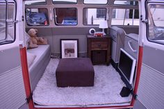 the inside of a van with a couch, television and other items on display in it