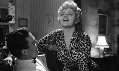 a woman in a leopard print robe is smiling at a man with his arm around her