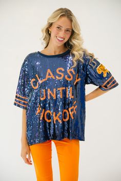 This CLASSY UNTIL KICKOFF TIGER SEQUIN TOP is the perfect way to show school spirit for the big game. Featuring a mix of navy and orange, this top let's you represent your team in style with a tiger patch accent on the sleeve. You'll be sure to stand out on gameday. All orders are currently shipping within 14 business days. To receive item quicker, expedited shipping is available at checkout. Varsity Tops For Cheerleading During Football Season, Navy Tops For Game Day During Sports Season, Navy Tops With Team Name For Football Season, Navy Team Name Football Tops, Collegiate Navy Top For Game Day, Collegiate Fall Fan Gear Tops, Navy Varsity Top For College, Navy Tops For Sports Events, Navy Sports Fan Top For Game Day