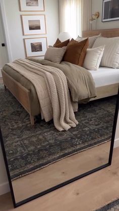 a large bed sitting on top of a wooden floor next to a mirror in a room