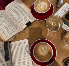 there are two cups of coffee and an open book on the table with other books