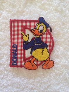 an embroidered patch depicting donald duck on a red and white checkered towel