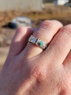 a person's hand with a ring on it that has three stones in the middle