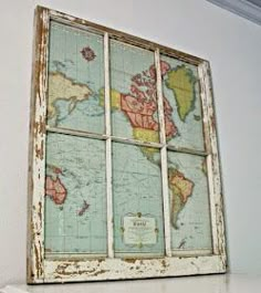 an old window with a world map on the glass in front of it, sitting on a shelf next to a white wall