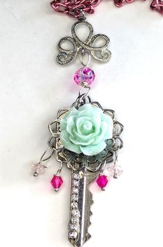 Repurposed real key strung on a pink aluminum chain, embellished with a large resin rose, filigree component and rhinestone chain.   I have added small pink glass beads to compliment the chain. The chain is 19 inches long, the key pendant is 2 inches long.  The connector and beads and filigree add another inch or so for a total of 24 inches. A fund addition to your spring wardrobe. Old Keys Crafts Diy, Keys Crafts, Old Key Crafts, Key Crafts, Resin Rose, Old Keys, Old Key, Key Jewelry, Necklaces Handmade