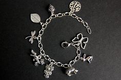 A collection of silver plated crochet themed charms have been dispersed around a shimmering silver plated bracelet chain in this handmade charm bracelet. This crochet charm bracelet is then completed with a lobster clasp and a 1/2 inch of chain at the end for adjustable sizing. Charms in this bracelet include a tree charm, pinecone charm, leaf charm, dragonfly charm, fox charm, owl charm, porcupine charm, rabbit charm, and butterfly charm. ● Sizing ● To determine your bracelet size, do a snug me Handmade Sterling Silver Bracelet For Gift, Bohemian Silver Personalized Bracelets, Handmade Alloy Bracelets Perfect As Gifts, Handmade Alloy Bracelets As Gift, Silver Charm Bracelet With Vintage Charm As A Gift, Handmade Silver Metal Charms, Silver Vintage Charm Bracelet Gift, Dainty Metal Charm Bracelet With Dangling Charms, Dainty Silver Charm Bracelet With Dangling Charms