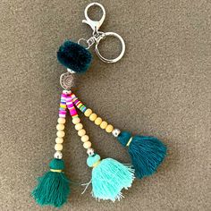 a key chain with tassels and beads hanging from it's side on the floor