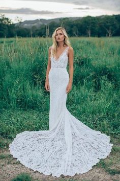 a woman is standing in the grass wearing a white dress and looking off to the side