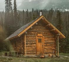 a log cabin in the woods with mountains in the background