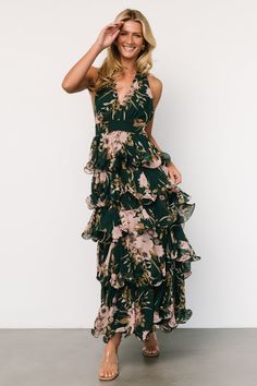 a woman in a green floral dress posing for the camera with her hand on her head