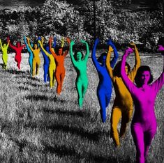 a group of people that are standing in the grass with their arms up and legs spread out