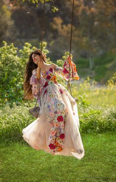 a woman in a dress swinging on a swing