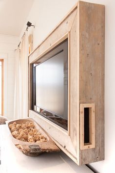 a tv mounted on the side of a wooden cabinet next to a bowl filled with food