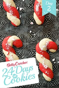 four cookies with red and white icing are on a black tray next to a sign that says betty crocker's forty days cookies