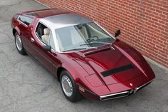 a red sports car parked next to a brick wall