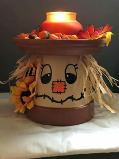 a pot with a candle on top of it that is decorated like a scarecrow