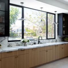 a large kitchen with marble counter tops and wooden cabinets, along with black framed windows