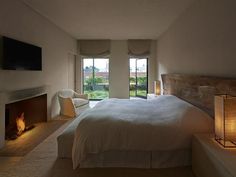 a bedroom with a bed, fireplace and large windows in it's center area