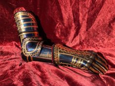 an elaborately decorated glove is laying on a red cloth