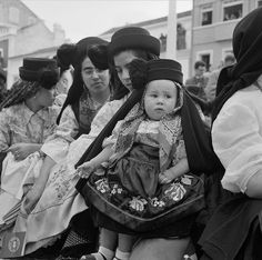 a group of people sitting next to each other on a bench in front of buildings