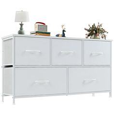 a white dresser with several drawers and a christmas tree on top, against a white background