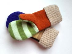 three knitted mittens sitting next to each other on top of a white surface