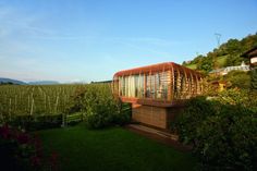 a wooden structure sitting in the middle of a lush green field next to a house