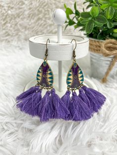 The Fringe Dreams Earrings will make sure you stand out in any crowd. This eye-catching dangle earring features a teardrop shape, with a gold, teal, and purple design, with a unique purple fringe detail. With this bold design, you'll add a dramatic statement to any look. Style: Dangle Earrings Color: Purple, teal, gold, and taupe Size: Purple Dangle Tassel Jewelry, Bohemian Purple Dangle Tassel Earrings, Purple Dangle Jewelry With Tassels, Teardrop Tassel Jewelry, Purple Drop Earrings For Festival, Purple Bohemian Tassel Earrings For Party, Purple Teardrop Earrings, Purple Teardrop Bohemian Earrings, Bohemian Purple Tassel Earrings