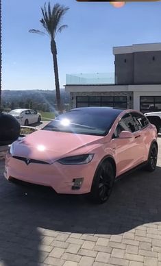 a pink tesla parked in front of a building