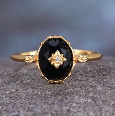 a close up of a black stone ring on top of a rock with a diamond in the center