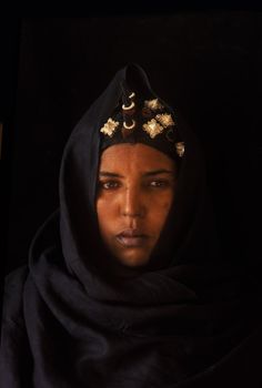 a woman wearing a black headscarf with gold decorations on her head and eyes