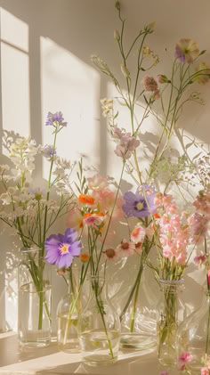 several glass vases filled with different colored flowers