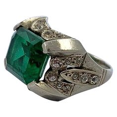 Art Deco silver ring, featuring a lovely emerald green paste stone in an open back setting, surrounded by clear paste stones. Circa 1930s. The ring is not stamped, but tests for silver. Ring size UK I, US 4 1/4, inside diameter 1.55cm. The green stone is slightly loose in the setting, but is held well in place. This is a beautiful Art Deco emerald green ring in a style typical of the era. Emerald Silver Ring, Art Deco Silver, Green Ring, Green Rings, Green Stone, Emerald Green, Fashion Rings, Beautiful Art, Open Back