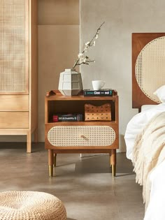 a bed room with a neatly made bed next to a night stand and wicker furniture