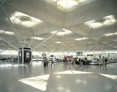 people are standing in an airport waiting for their luggage