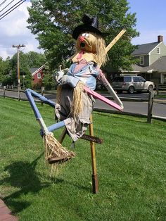 a scarecrow sitting on top of a wooden pole