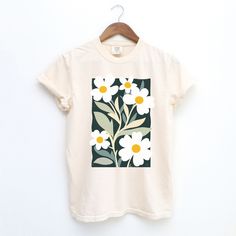 Add a touch of artistic charm to your wardrobe with this 100% cotton Comfort Colors T-shirt, featuring a vibrant graphic of daisy flowers inspired by Henri Matisse's iconic cutout style. A light washed/worn effect has been added to the design. Soft, durable and with an unique design, this tee combines comfort with bold, expressive art for a one-of-a-kind look. Perfect for everyday wear or as a unique gift. The soft-washed, garment-dyed fabric brings extra coziness to your wardrobe while the relaxed fit makes it an excellent daily choice. The double-needle stitching throughout the tee makes it highly durable while the lack of side-seams helps the shirt retain its tubular shape. ✔️ 100% Cotton Comfort Colors T-shirt ✔️ Soft, durable fabric with a relaxed fit ✔️ Ideal for casual wear or gifti White Watercolor Print T-shirt For Spring, Spring Watercolor Print Cotton T-shirt, Botanical Graphic Print Cotton Shirt, Artistic Floral Print Tops For Spring, Artistic Cotton Tops For Spring, White Botanical Screen Print Tops, White Botanical T-shirt With Floral Print, White T-shirt With Botanical Print, Botanical Cotton Shirt With Floral Print