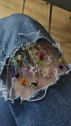 a pair of jeans that have flowers on them and some beads in the back pocket