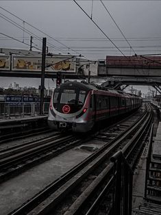 a train traveling down tracks next to a loading platform with lots of power lines above it