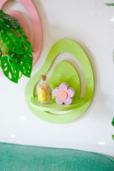 there is a green shelf on the wall next to a potted plant and a bottle