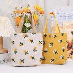 two yellow and white bags sitting next to each other on top of a table with flowers