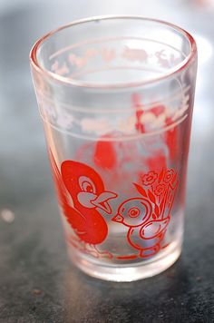 a shot glass sitting on top of a table with red and white designs in it