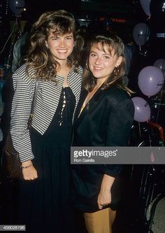 two women standing next to each other in front of balloons