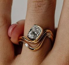 a woman's hand with a gold and white diamond ring on top of her finger