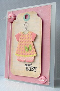 a card with a baby's clothes hanging from the front, and a tag attached to it