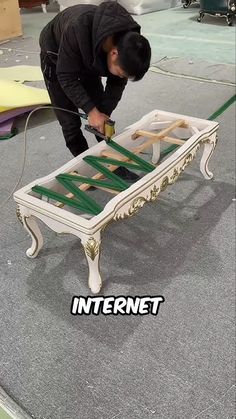 a man is working on an old table with green tape around the legs and feet