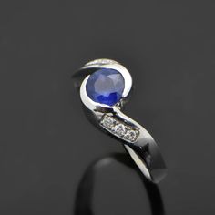 a blue sapphire and diamond ring on a black background, with the stone in the middle