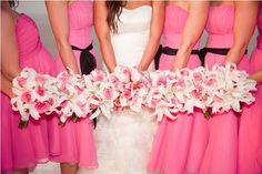 a group of women standing next to each other in pink dresses holding bouquets with white and pink flowers